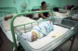 A new born baby rests beside his mother Dailyn Fleite (L), 29, at the Ana Betancourt de Mora Hospital in Camaguey, Cuba, June 19, 2015. The World Health Organization on Tuesday declared Cuba the first country in the world to eliminate the transmission of HIV and syphilis from mother to child. Picture taken June 19, 2015. REUTERS/Alexandre Meneghini